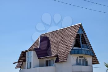 Detached house with a roof made of steel sheets. Roof metal sheets. Modern types of roofing materials.