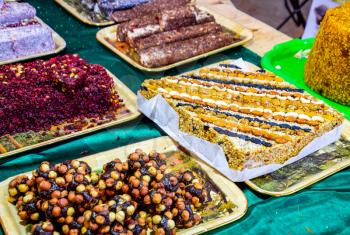 Marmalade balls, sprinkled with dried berries and sweet sawdust. Balls with nuts and marmalade. Trays with Indian sweets. Kozinaki and marmalade.