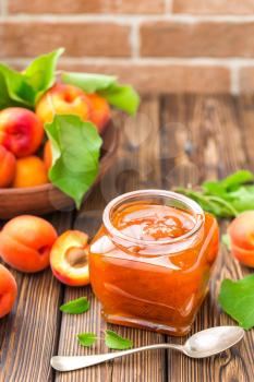 Apricot jam in a jar and fresh fruits with leaves