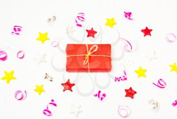 Present in the frame of stars, confetti on a white background. The composition of the present in red wrapping paper and stars, Christmas decorations. Christmas, New Year's ,birthday background
