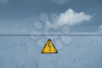 Obstruction to mark unsafe, high voltage and grid. Danger of death. The sky behind the fence