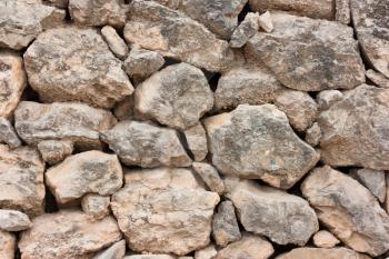 Close-up of a wall of rough cobblestones in a row, brown background of natural stones