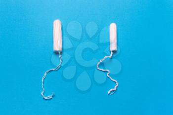 tampon on a blue background. The view is flat. Concept of critical days, menstruation