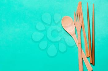 Natural, ecological, Organic wooden fork, spoon, cutlery on a green background. Concept zero waste, environmental pollution.