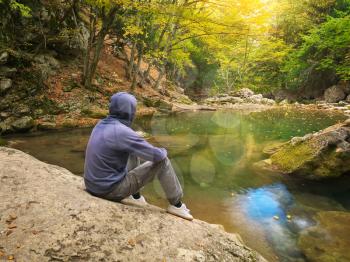 Man in autumn forest and river lake. Landscape and nature scene.
