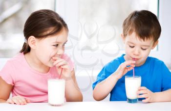 Cute little girl and boy drink tasty fresh milk