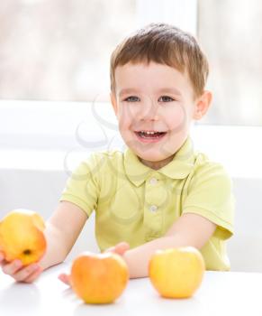 Portrait of a happy little boy with yellow apples