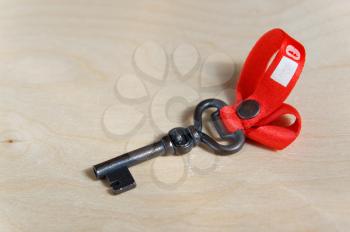 Black metal key figure with red ribbon on wooden table