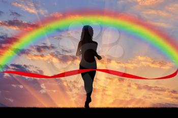 Runner, rainbow, sport. Woman runner crosses the red tape on the background of the rainbow