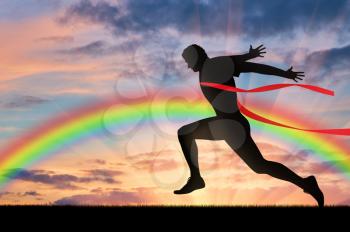 Runner, rainbow, sport. Male runner crosses the red tape on the background of the rainbow