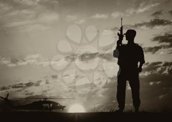 Concept of terrorism and war. Silhouette of a terrorist with a weapon against a background of military helicopters