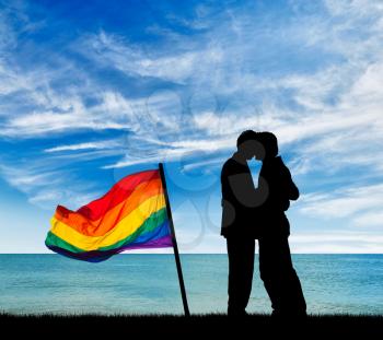 Concept of gay people. Silhouette happy gay kiss on a background seascape and a rainbow flag