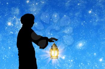 ?oncept of Islamic culture. Silhouette of a man with a lamp in his hand against the background of the starry sky