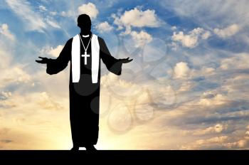 Concept of religion. Priest praying silhouette against the evening sky in the sun