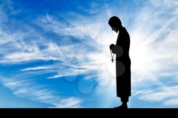 Concept of religion. Silhouette of a priest with a cross in his hand against a beautiful sky