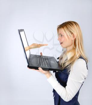 Concept of emotion and advertising. Surprised woman holding a laptop with hand offers hands
