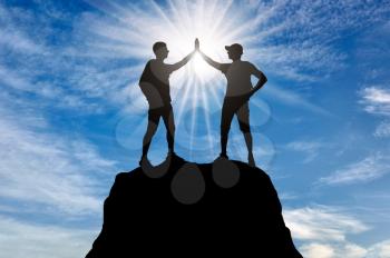 Two happy climbers on the top of the mountain, make a gesture with their hands, give five. Conceptual image