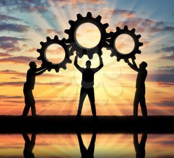 Silhouette of the three men holding the gears put them together in one gear. The concept of mutual aid