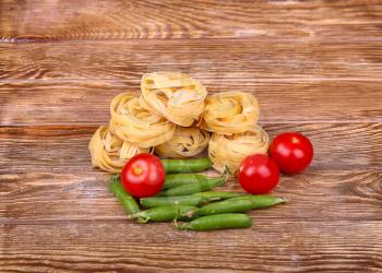 Pasta on the wooden background with tomato, lettuce 