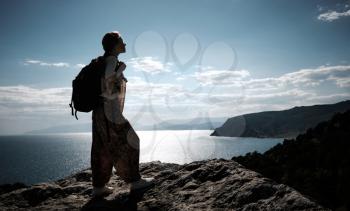 Hiker with backpack standing on top of a mountain with raised hands and enjoying view. Woman