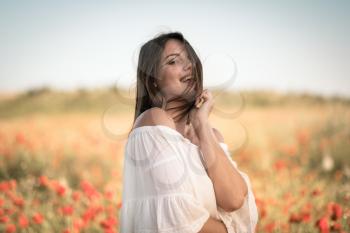 beautiful girl in a poppy field at sunset. concept of freedom. Closeup portrait of an attractive woman at sunset