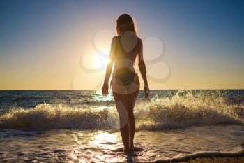 young slim beautiful woman on sunset beach, playful, dancing, running, bohemian outfit, indie style, summer vacation, sunny, having fun, positive mood, romantic, splashing water, silhouette, happy, photo toned