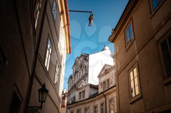 Prague, Czechia - 10.08.2019. The architecture of the old city of Prague. Ancient buildings, cozy streets. Man hanging out. an artwork by David Cerny in old town, depicting Sigmund Freud.