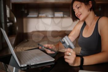A young asian woman holds a credit card and uses a laptop. The concept of online shopping. black Friday or other sale