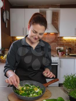 Healthy eating lifestyle concept portrait of beautiful young redhair woman preparing tasty food, green hot shakshuka cooked with love