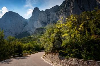 asphalted road in the mountains, beautiful sunshine, summer vacation time. Vintage toning. Travel background. Highway in european mountains