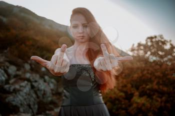 beautiful furious scandinavian warrior ginger woman in grey dress with metal chain mail. woman showing middle finger - gesture of fuck, expression, provocation and rude attitude.