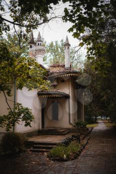 small mosque in the botanical garden. the beginning of autumn, beautiful dark leaves frame the laced building