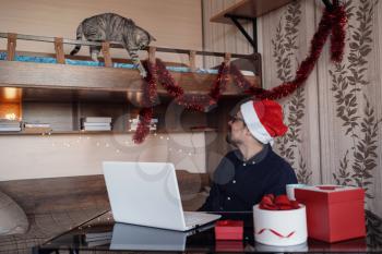 happy young man with funny tabby gray cat at home. Christmas gift boxes, New Year winter sale discount. Safe ordering delivery at quarantine.