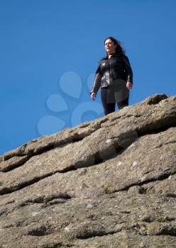 Haytor or Hay Tor rocks with single female hiker on the top of the granite rock on Dartmoor, Devon, England, United Kingdom