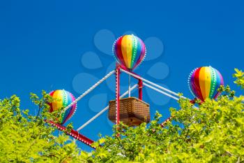 Colorful lighted balloon shapes above baskets on childrens fairground ferris wheel