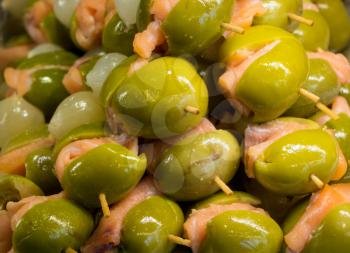 Green olives and salmon on plate of hors-d'oeuvres or entradas in food counter in Spanish market in Madrid