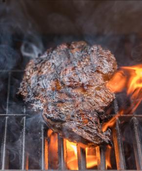 Close up of large piece of steak or beef flaming on barbeque