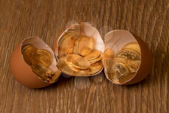 Selection of pure gold USA treasury coins in broken egg shell illustrating financial security of a retirement nest egg