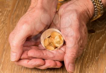 Senior man's hand holding a selection of pure gold USA treasury coins in broken egg shell illustrating financial security of a retirement nest egg