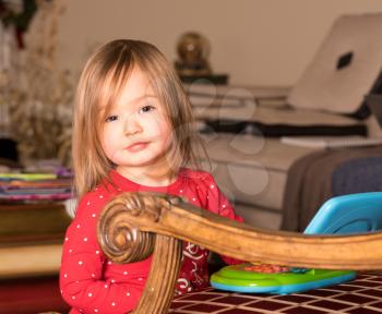 Young baby girl playing with a small plastic toy computer on a chair in her living room
