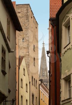 Cathedral tower and spire in distance along narrow street in the medieval town of Regensburg, Bavaria, Germany