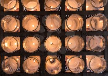 Pattern of votive candles in glass jars for prayer and remembrance in Catholic church
