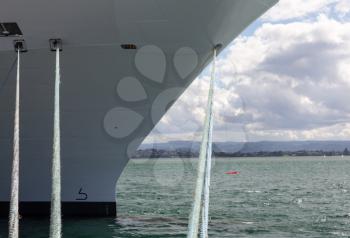 Bow of a cruise ship docked in the harbor with the focus on the bollards and ropes mooring the boat to the harbour wall