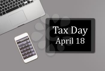 Overhead clean desk for laptop, smartphone and tablet computer with message for tax day 2017 as April 18
