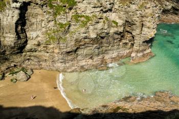 Two small girls and dog playing on beach and in sea near Tintagel, Cornwall, England, UK