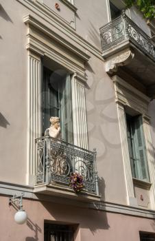 Statue on a wrought iron balcony in ancient district or neighborhood of Plaka in Athens by the Acropolis