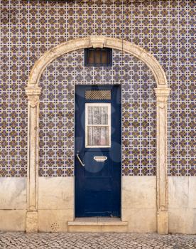 Decorative ceramic tiles on around a blue door entrance to home in Alfama district of Lisbon, Portugal