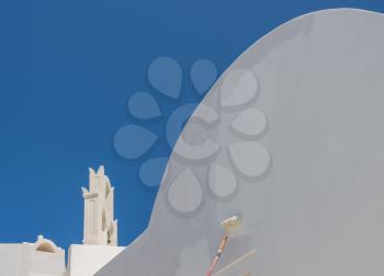 White paint being applied by roller to traditional house in Santorini