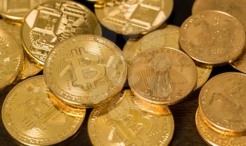 Pile of gold coins alongside bitcoins to illustrate investment choice