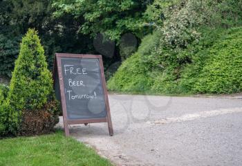 Humorous sign on blackboard outside pub saying Free Beer Tomorrow